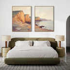 A modern bedroom with a green upholstered bed, white bedding, and gold nightstands features "Coastal Grandeur - Set of 2" canvas prints above the bed, adding a serene coastal vibe in a soft, neutral palette.