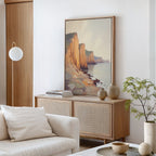 A modern living room in neutral tones featuring a wooden sideboard, ceramic vases, books, a potted plant, and the Coastal Grandeur Canvas Art - Vertical depicting seaside cliffs hanging above the sideboard.