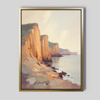 Coastal Grandeur Canvas Art - Vertical features sunlit seaside cliffs above a calm sea, rocky shoreline in the foreground, and soft hazy clouds. Warm tones create a serene, peaceful coastal wall art for your space.