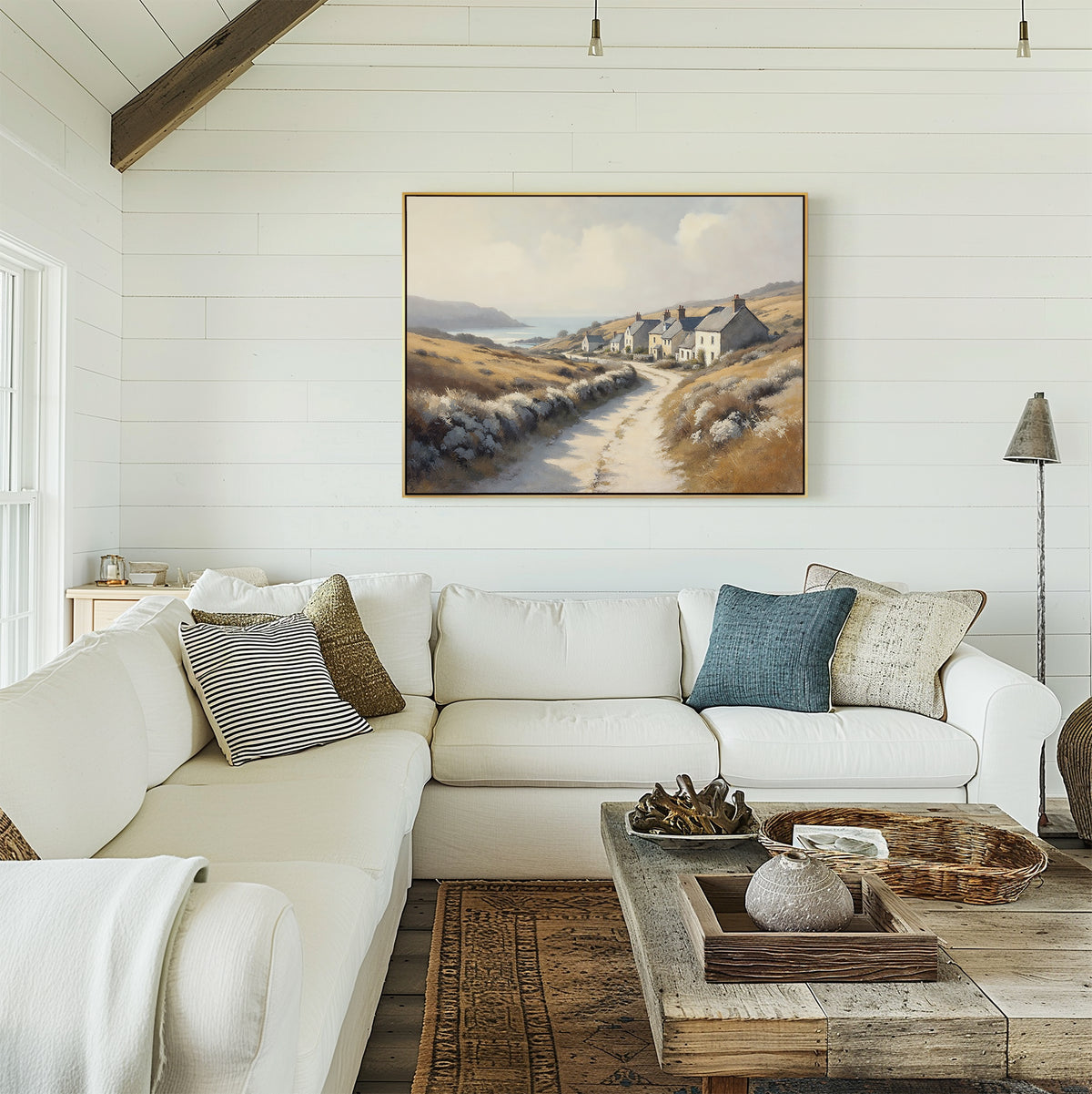 A bright, airy living room with a white sectional sofa, assorted pillows, a rustic wood coffee table with decor, and the Coastal Haven Canvas Art - Horizontal framed on the white shiplap wall.
