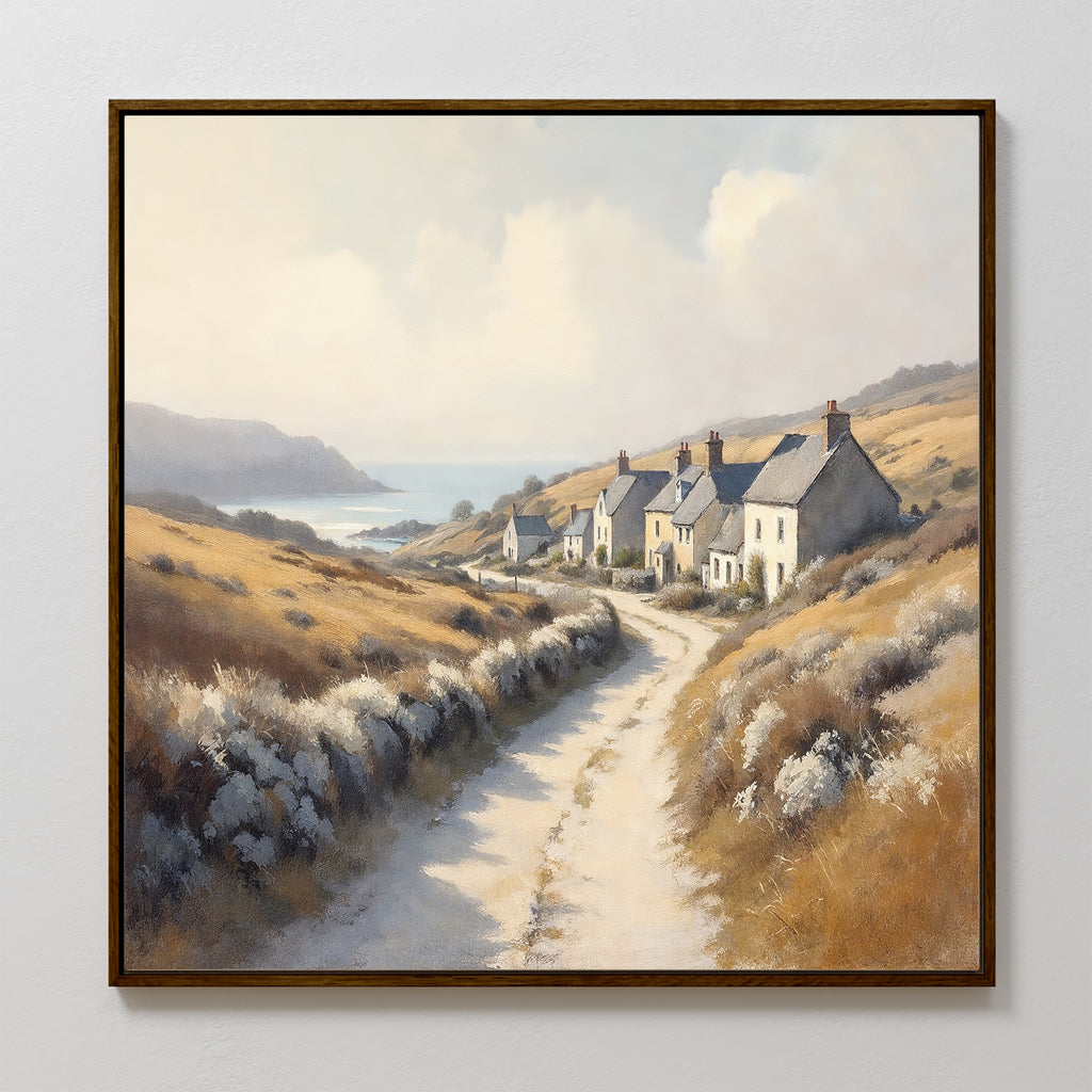 The Coastal Haven Canvas Art - Square features a framed print of a winding dirt road to stone cottages among golden hills, with sea and cliffs in the distance under a partly cloudy sky, adding rustic coastal charm to your space.
