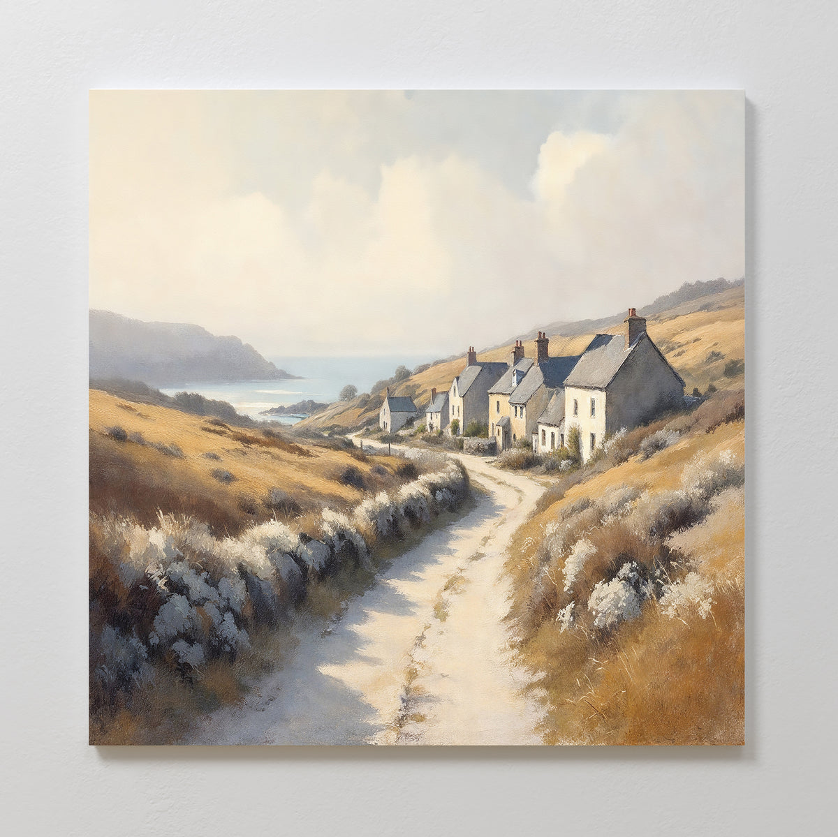 Coastal Haven Canvas Art - Square features a rural landscape with a winding dirt road, white cottages, golden fields, and distant coastal hills beneath a bright sky—perfect rustic wall art for any space.