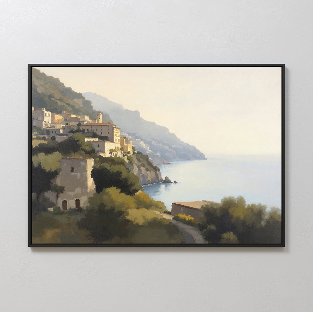 The Italian Reverie Canvas Art - Horizontal features a framed painting of a coastal village with cliffside architecture, calm blue water, distant cliffs, lush greenery, and warm sunlight beneath a hazy sky.