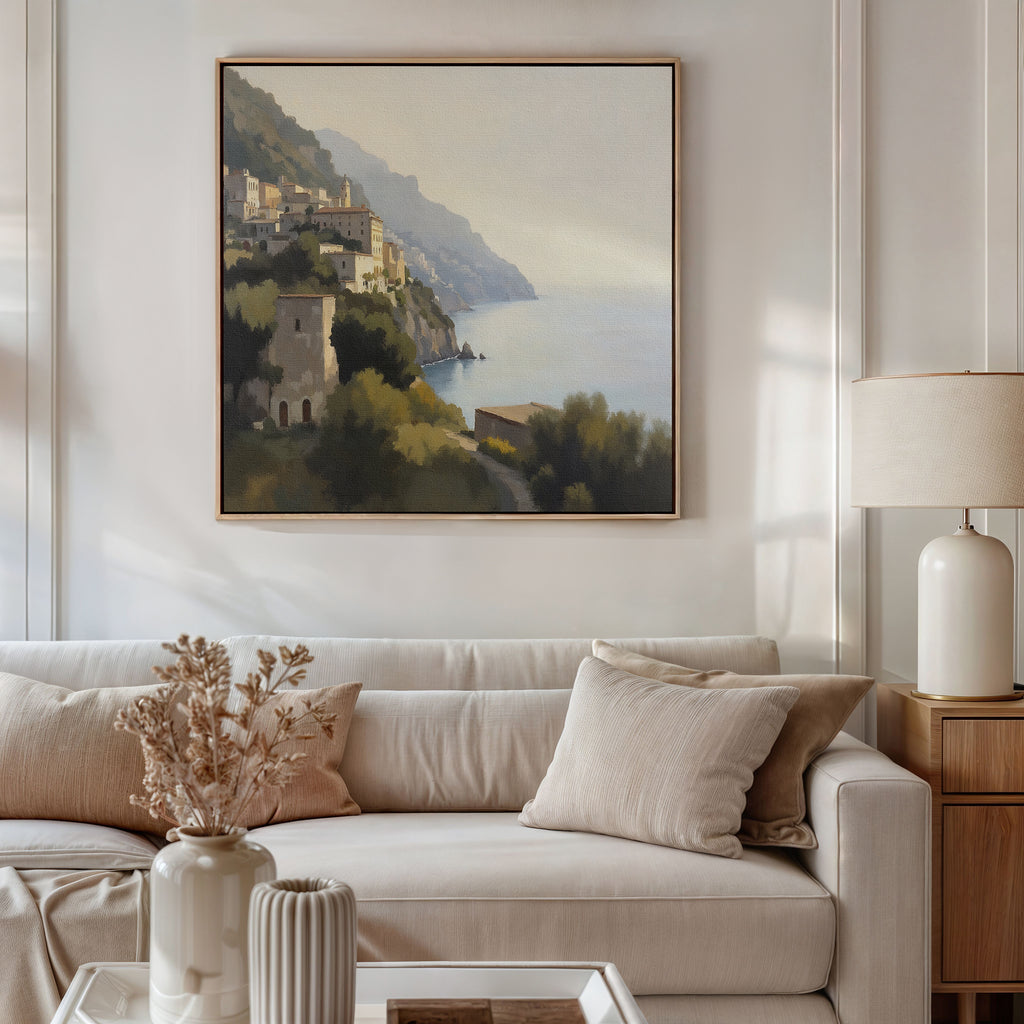 A cozy living room features a white sofa, beige cushions, and a side table with a lamp and dried flowers. Above the sofa hangs the Italian Reverie Canvas Art - Square, bringing elegant Mediterranean style to the inviting space.