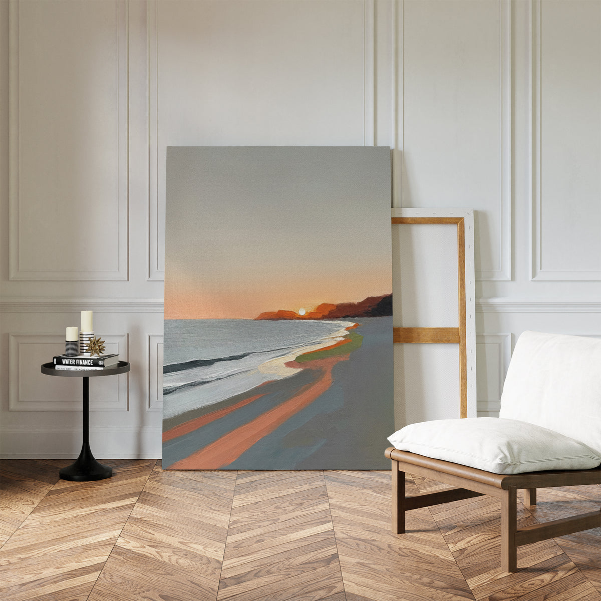 The Coastal Reverie Canvas Art - Vertical, featuring orange and gray sunset hues, leans against a white wall in a chic room with herringbone floors, a cushioned chair, and a black side table for tranquil home decor.