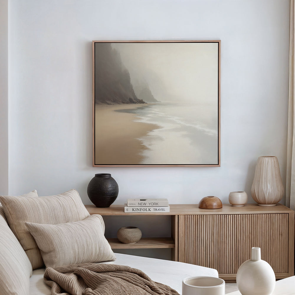 A serene living room features a beige sofa, striped pillows, and a wooden sideboard with vases. Above, the Coastal Silence Canvas Art - Square adds to the natural palette, enhancing the tranquil atmosphere of the space.