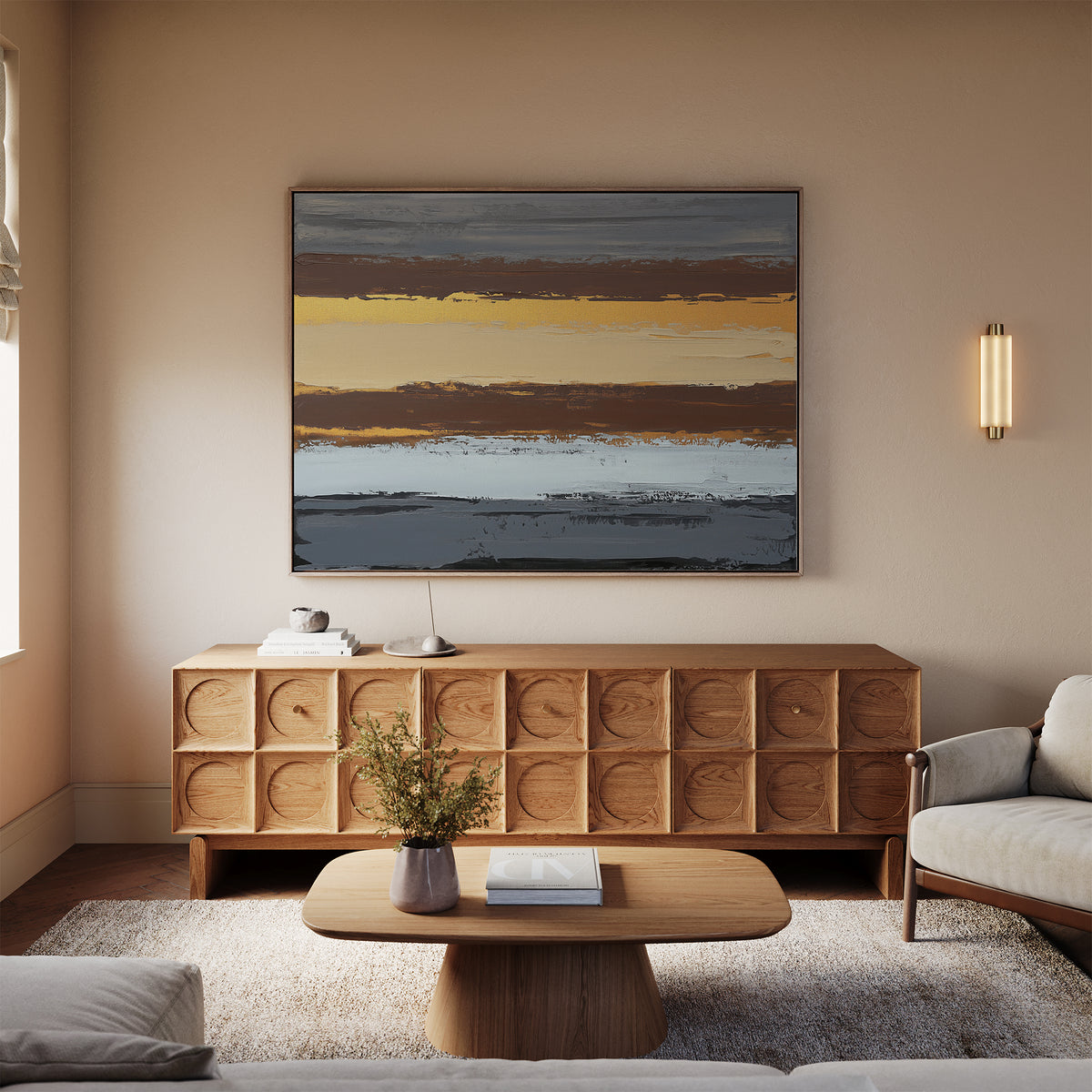 A cozy living room features a modern wooden sideboard, a low coffee table with a flower vase, a beige sofa, and the Coastal Strata Canvas Art - Horizontal above the sofa, adding earthy sophistication with its blue, yellow, gray, and brown stripes.