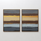 The "Coastal Strata - Set Of 2" features abstract prints with layered stripes in brown, yellow, grey, blue, and gold. Their textured look adds earthy sophistication and refined style to any white wall.