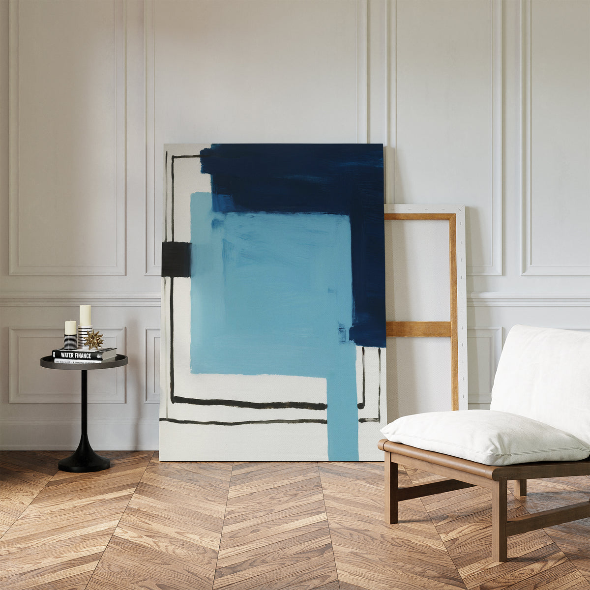A modern living room with herringbone wood floors, white paneled walls, a minimalist white chair, a small round table with candles, and the Cobalt Intersection Canvas Art - Vertical leaning against the wall for contemporary decor.