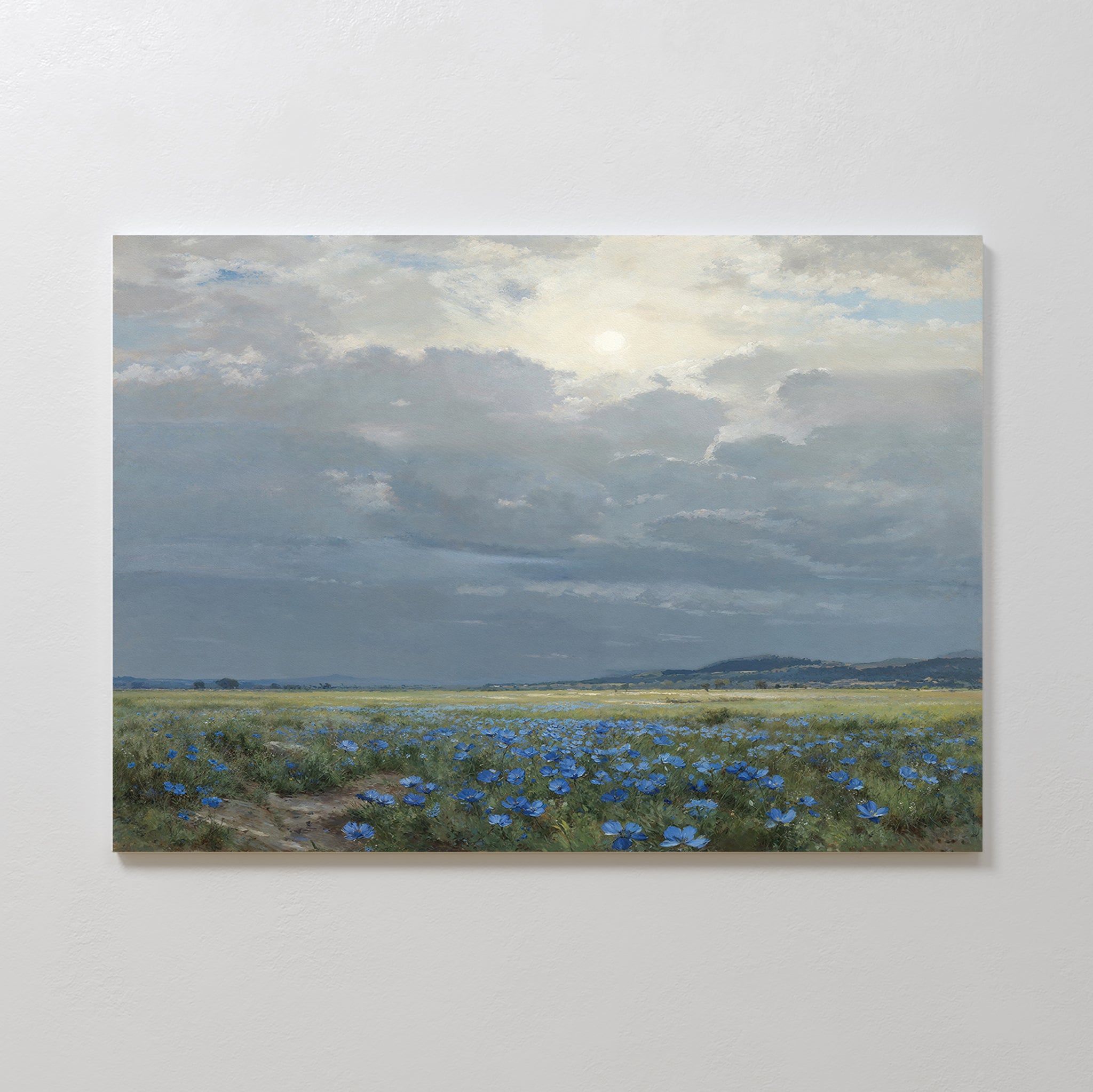 Enjoy the serene beauty of "Cornflower Fields Canvas Art - Horizontal," featuring a grassy field with blue wildflowers and distant hills under a sunlit cloudy sky—ideal for adding countryside charm to your home decor.