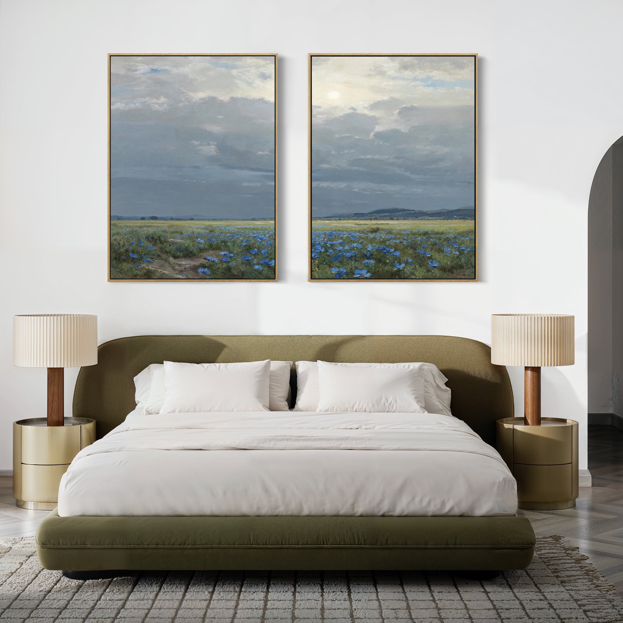 A modern bedroom features an olive green bed, white bedding, round nightstands with beige lamps, and above the bed hangs Cornflower Fields - Set of 2: large canvas prints of pastoral landscapes with cloudy skies and cornflower fields.