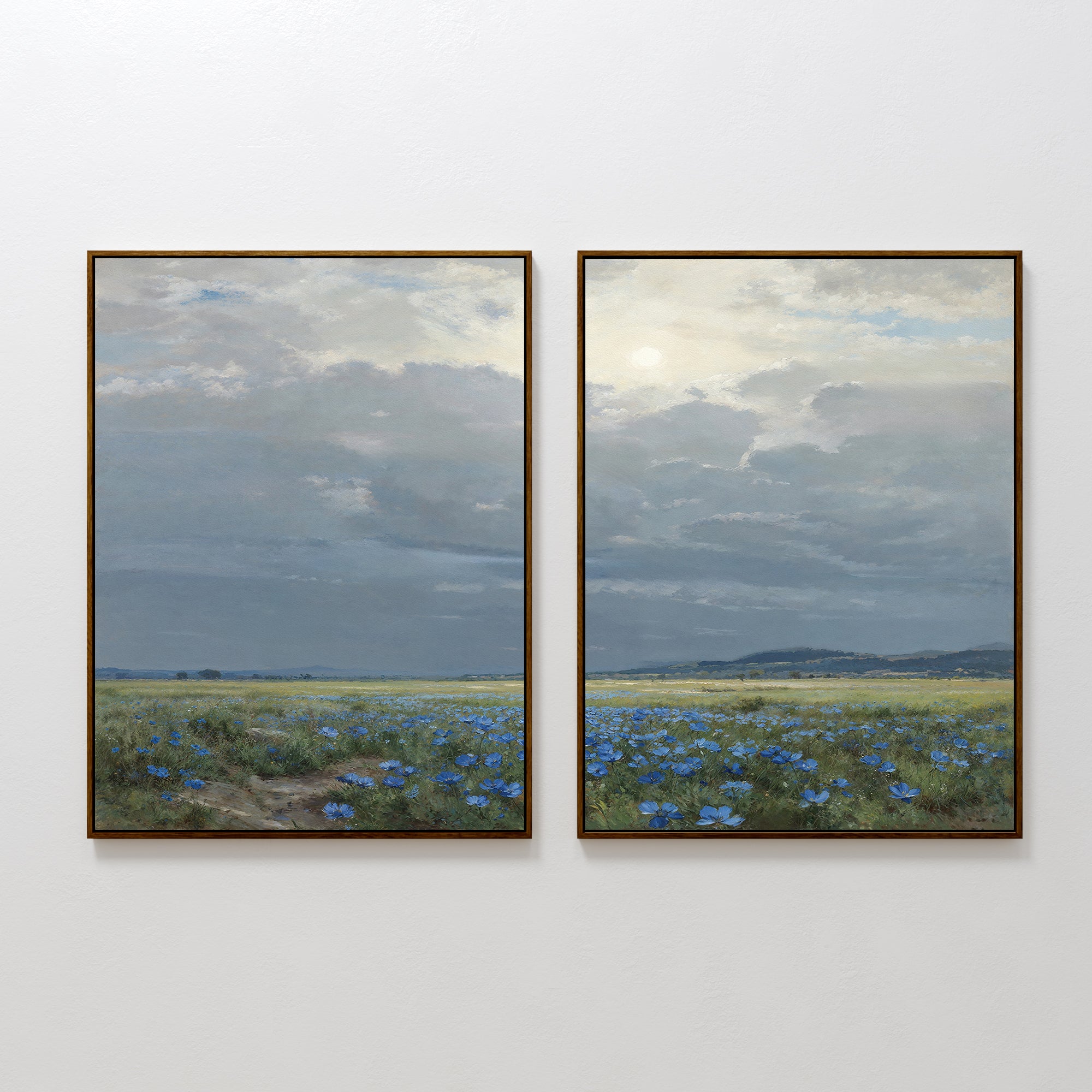The Cornflower Fields - Set of 2 features framed canvas prints showing a pastoral landscape with cornflower fields, distant hills, and gentle sunlight under a partly cloudy sky, displayed side by side on a white wall.