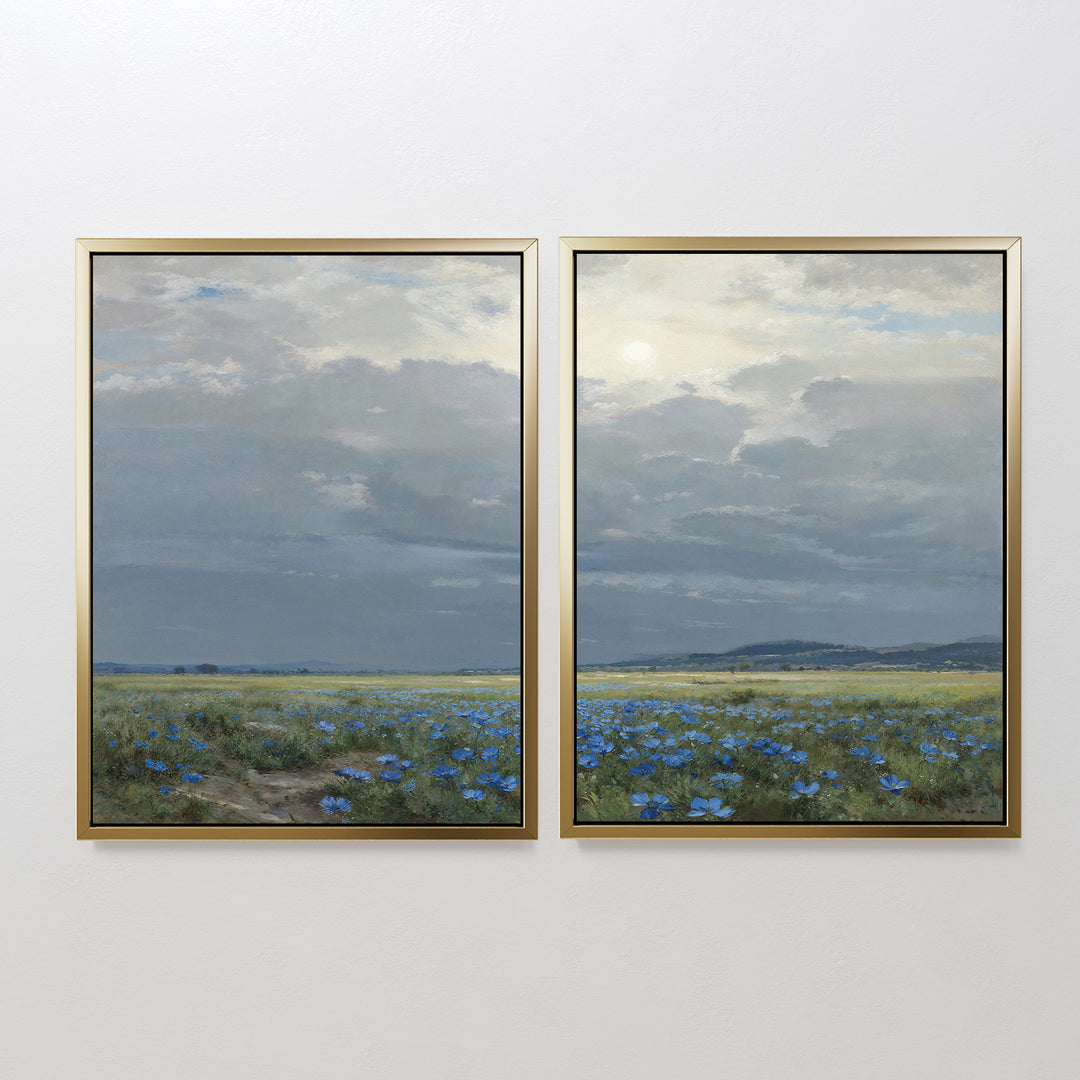 The Cornflower Fields - Set of 2 features framed canvas prints showing a pastoral landscape with wide cornflower fields, distant hills, and soft sunlight filtering through clouds against a white wall.