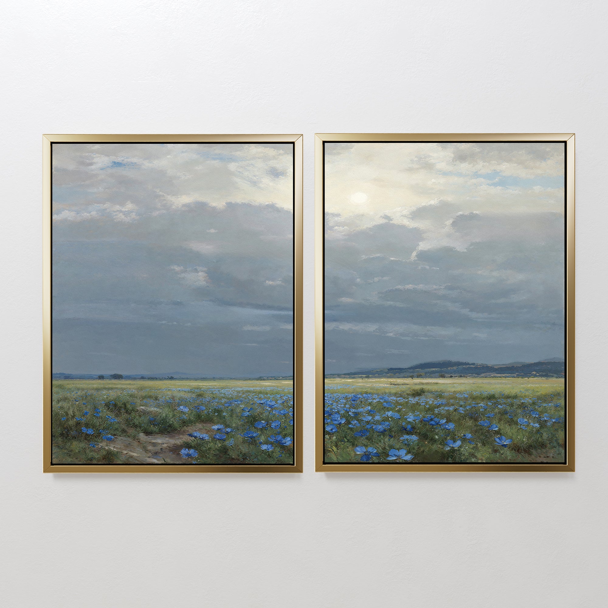 The Cornflower Fields - Set of 2 features framed canvas prints showing a pastoral landscape with wide cornflower fields, distant hills, and soft sunlight filtering through clouds against a white wall.