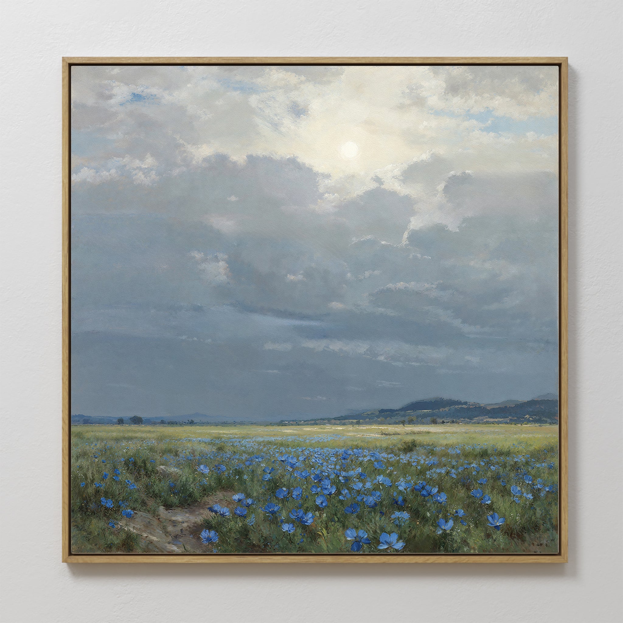 Add countryside charm to your space with "Cornflower Fields Canvas Art - Square," featuring blue wildflowers under a cloudy sky and sunlight, distant hills, and a peaceful muted palette—ideal for serene wall decor.