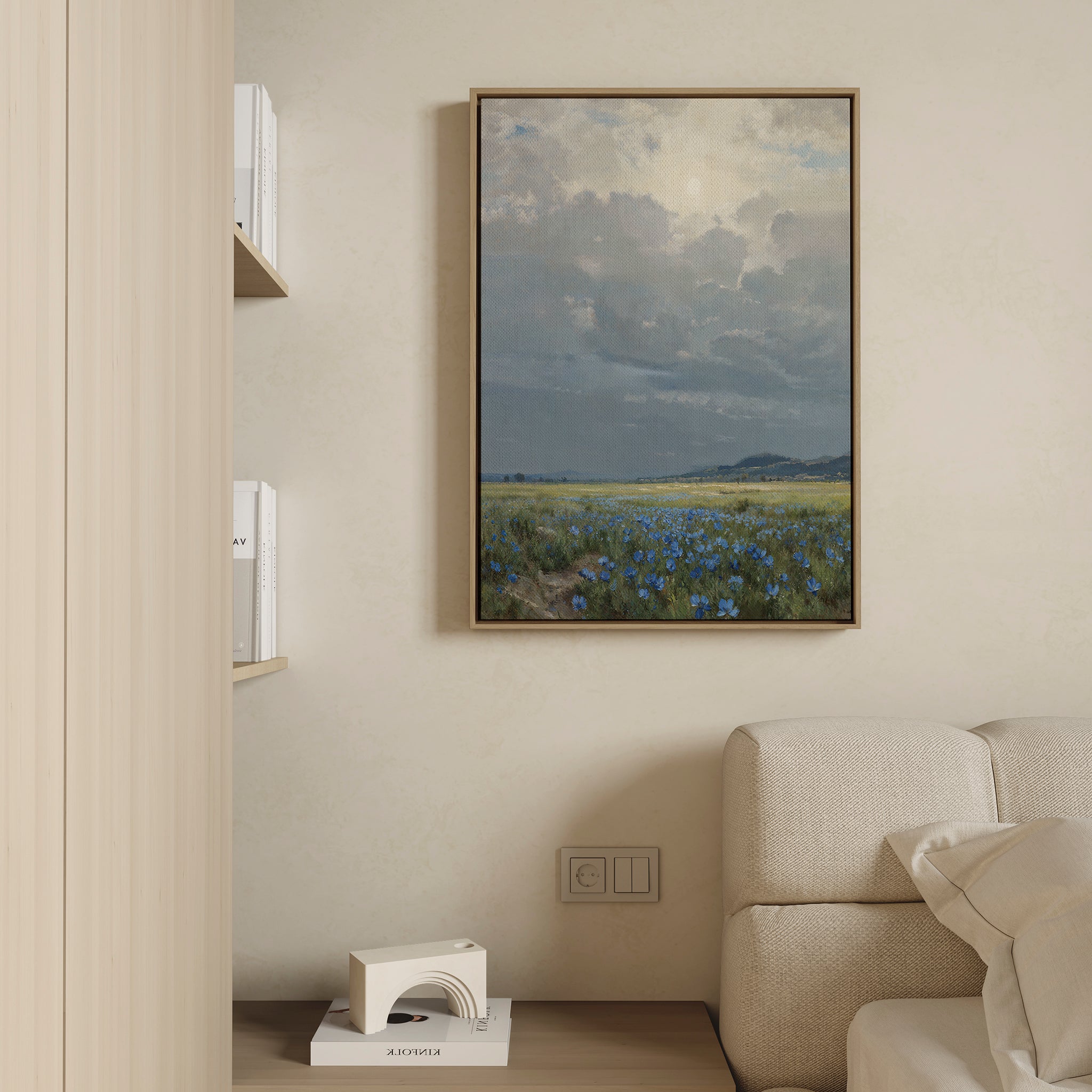 The Cornflower Fields Canvas Art - Vertical hangs on a beige wall above a light-colored sofa in a modern, minimalist living room, with shelves nearby holding books and a decorative object.