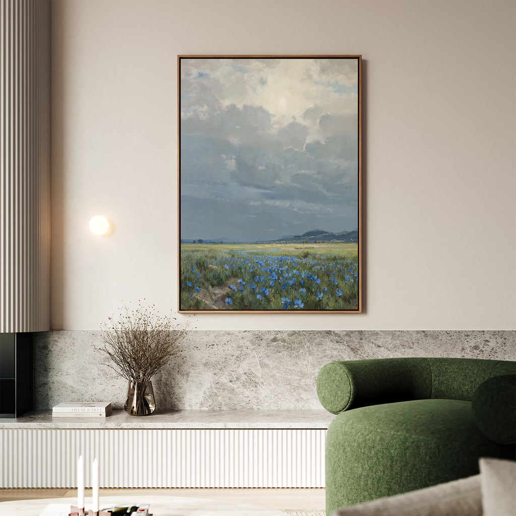 A modern living room featuring a green chair, marble accents, and the Cornflower Fields Canvas Art - Vertical depicting a cloudy sky over cornflower fields, displayed on a light-colored wall.