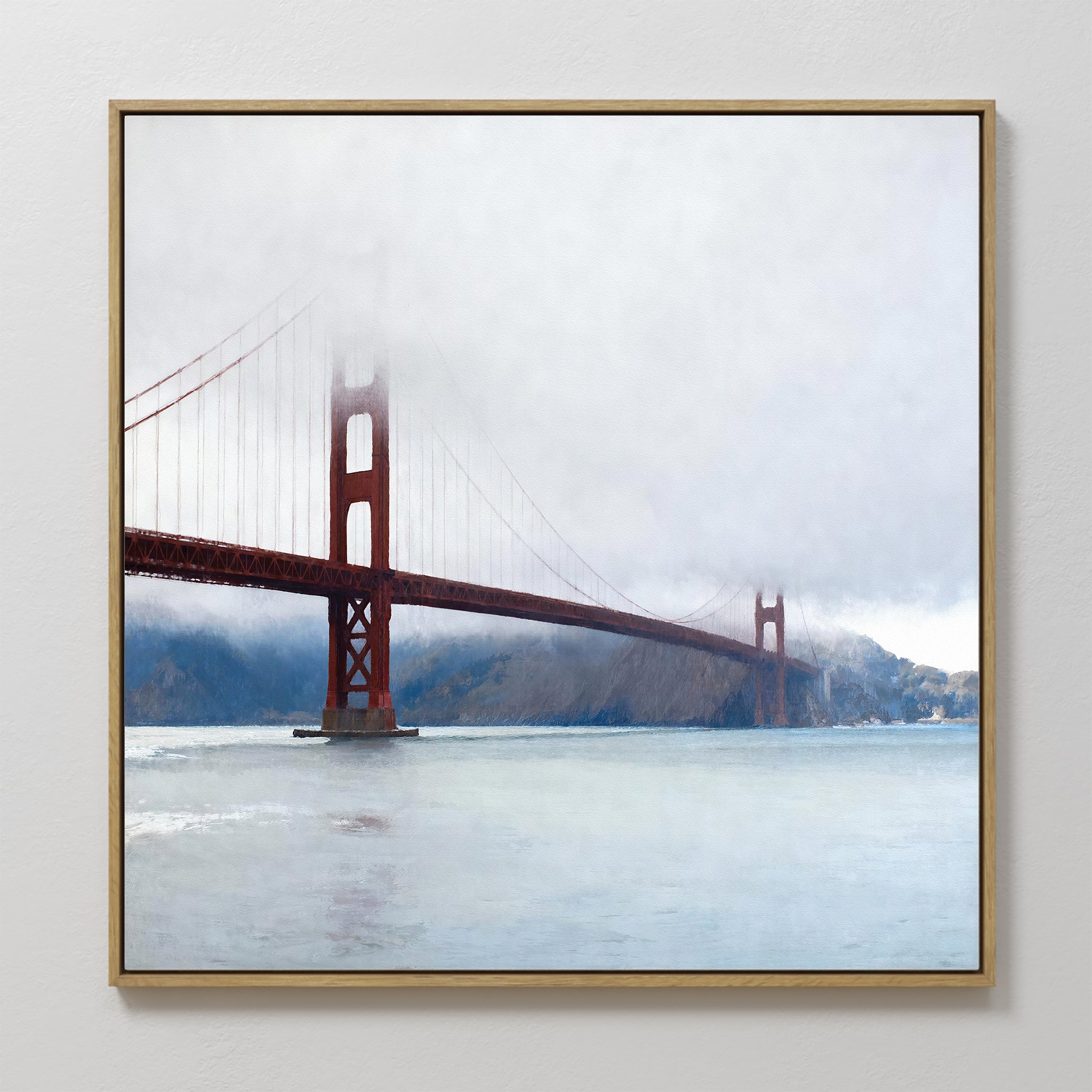 The Crimson Passage Canvas Art - Square captures the coastal elegance of San Francisco’s Golden Gate Bridge, partially veiled by fog, with calm waters and distant hills completing the serene scene.