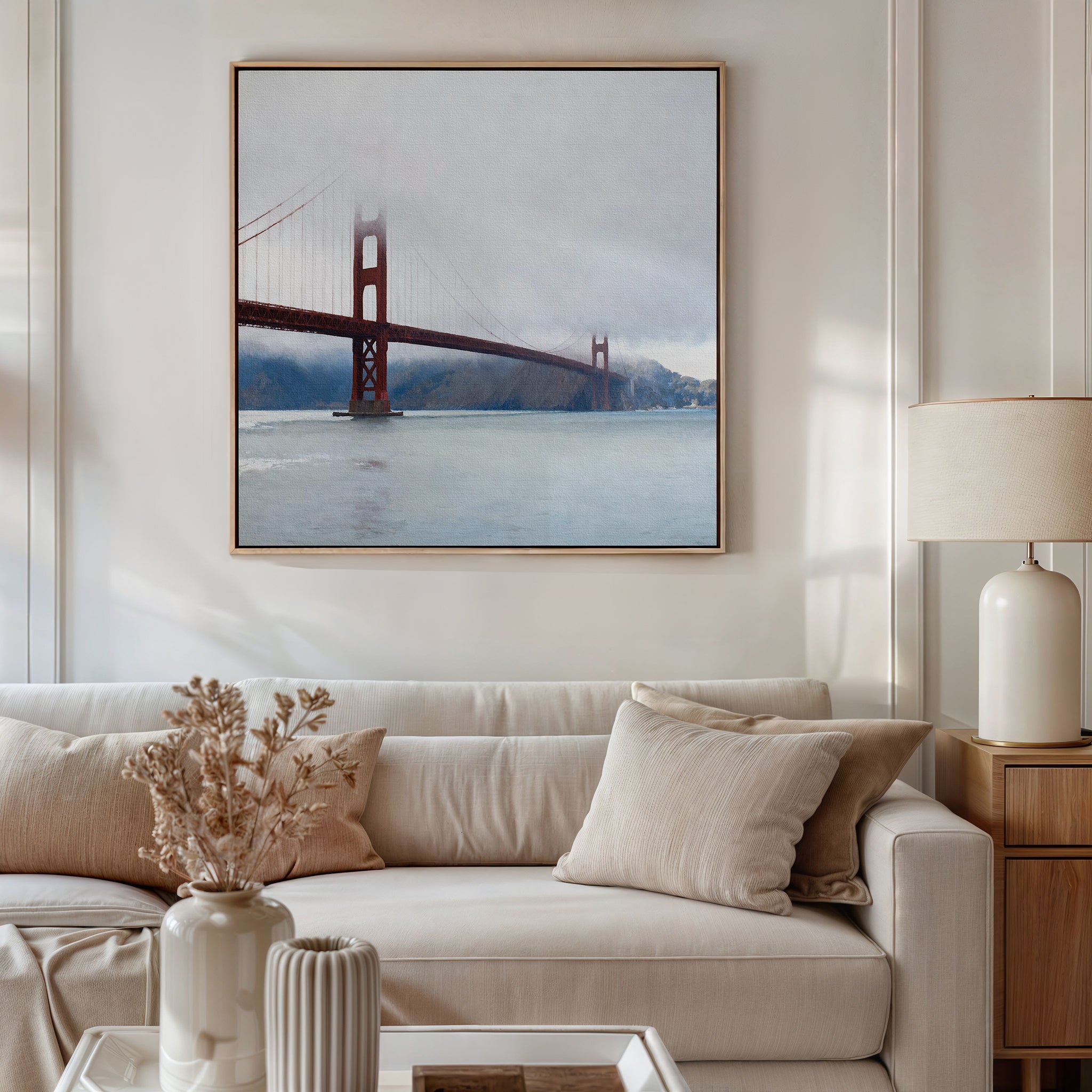 A beige, modern living room features a white sofa with neutral pillows, a lamp, and dried flowers in a vase. Above the sofa hangs the Crimson Passage Canvas Art - Square, bringing contemporary elegance to the serene space.