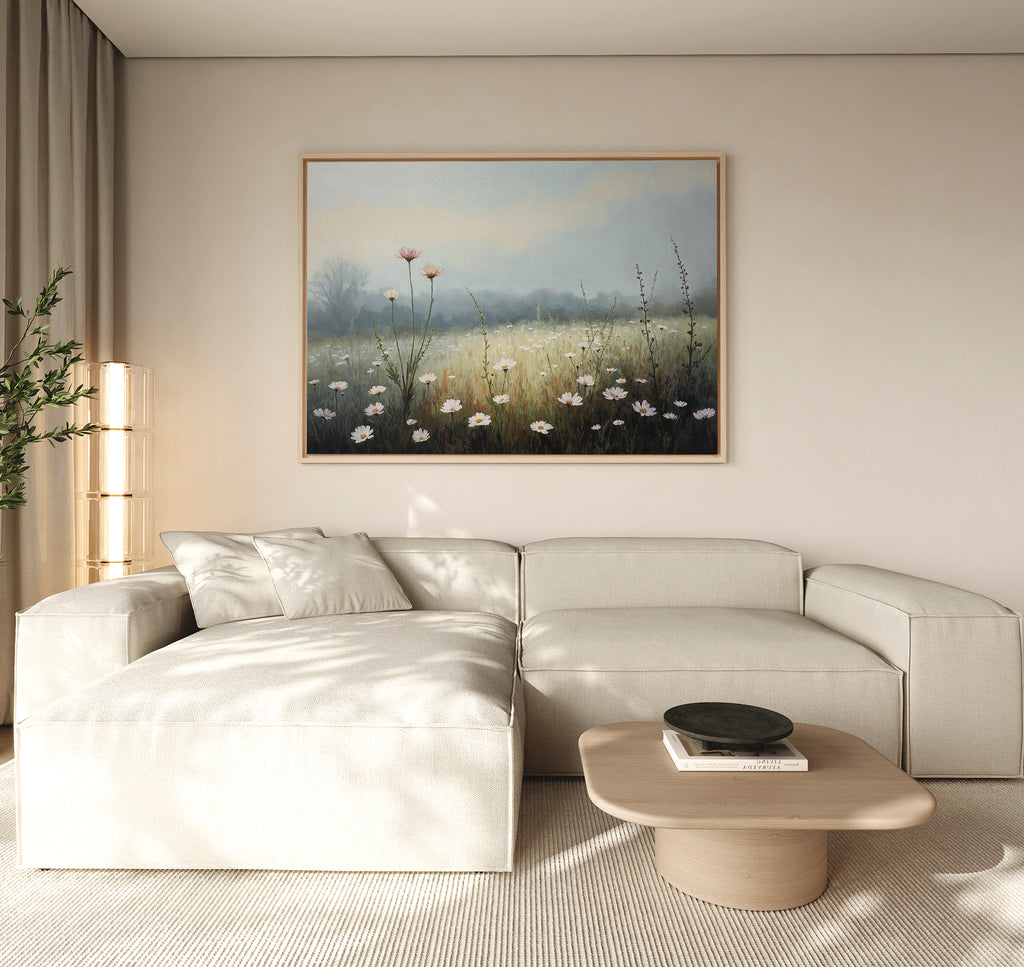 A modern living room features a beige sectional sofa, a light wood coffee table, and the Dawn Meadow Canvas Art - Horizontal displayed on a neutral wall, illuminated by soft natural light entering from the left.
