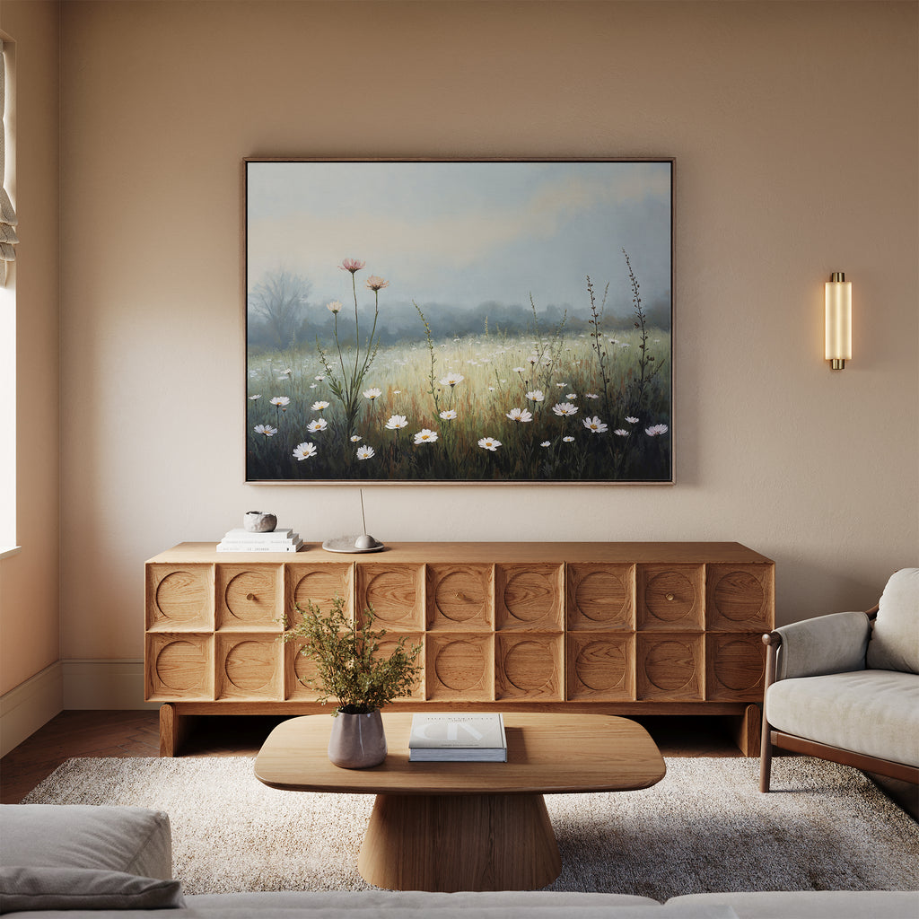A cozy living room with a wooden sideboard, coffee table, light sofa, and the striking Dawn Meadow Canvas Art - Horizontal. Soft natural light streams in through a window while a small vase of flowers adorns the table.