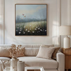 A bright, neutral-toned living room features a beige sofa with cream pillows and a side table with a lamp. Above the sofa hangs the Dawn Meadow Canvas Art - Square. Dried flowers in vases decorate the coffee table for botanical style.