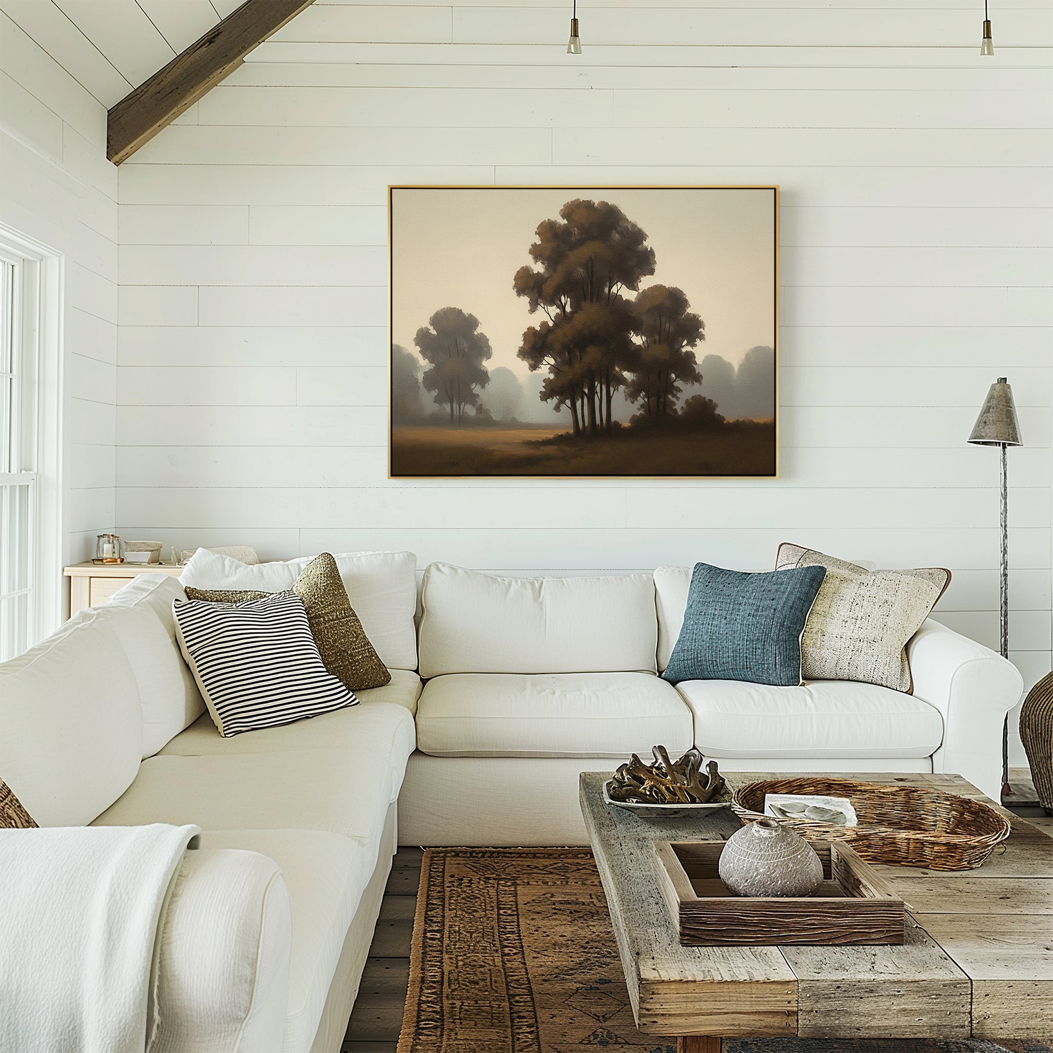 A cozy living room with white shiplap walls, a large white sectional sofa, patterned pillows, a rustic wooden coffee table, woven rugs, and the Dawn Silhouettes Canvas Art - Horizontal featuring trees hanging above the sofa.