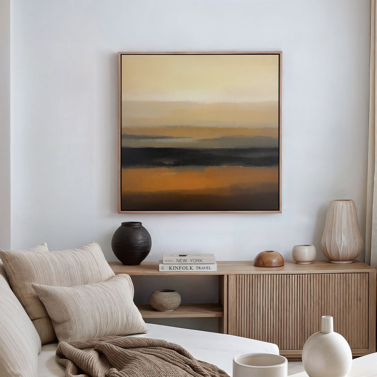 A modern living room features a light beige sofa, neutral cushions, and a wooden sideboard with vases. Above, the Desert Mirage Canvas Art - Square brings warm earth tones in an abstract style to the space.
