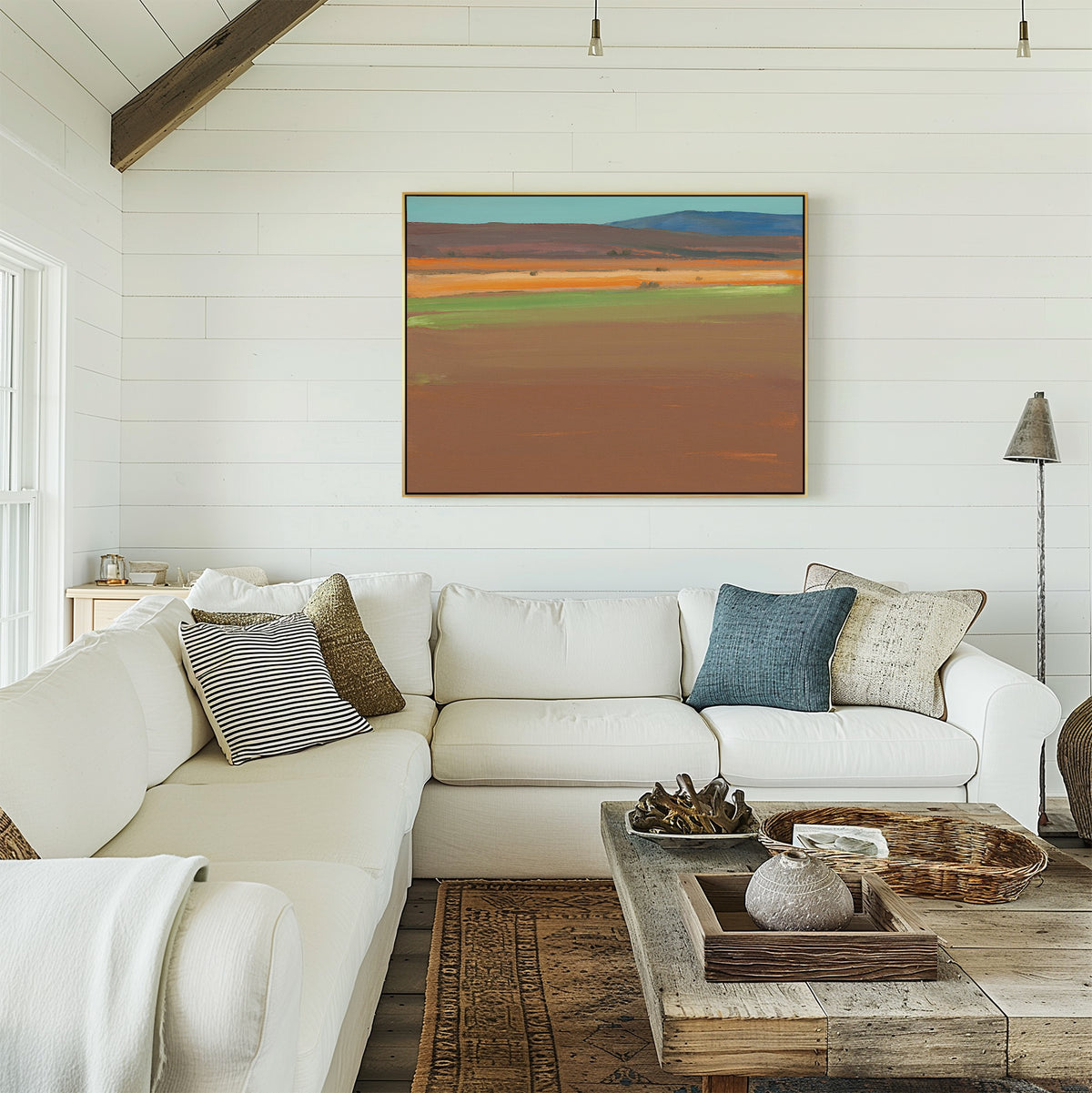A bright, modern living room features a white sectional sofa, textured pillows, and a rustic wood coffee table. The Desert Plains Canvas Art - Horizontal adds Southwestern warmth as earthy tones and natural materials create a cozy vibe.