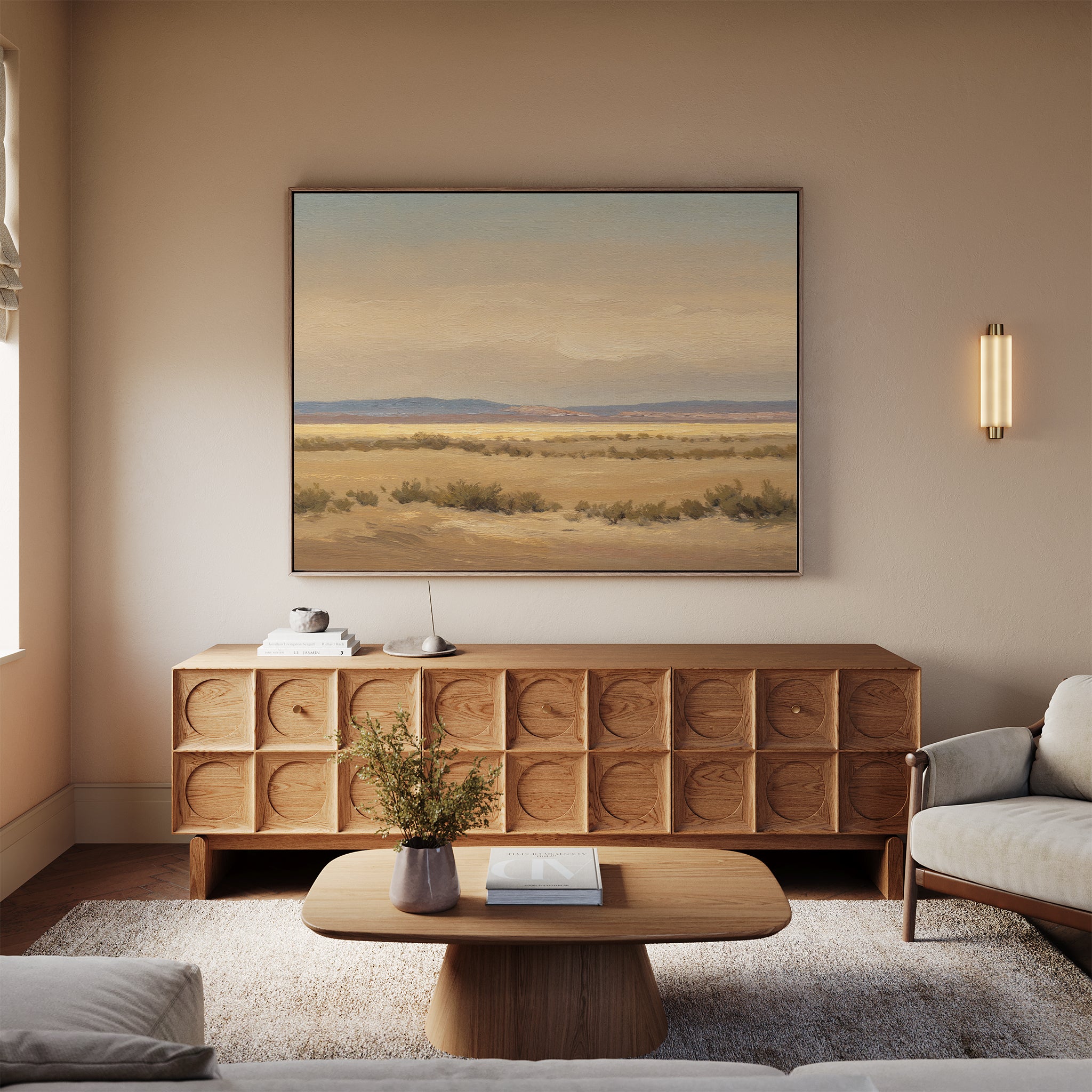 A cozy living room with a light wood coffee table, sculpted wood sideboard, neutral sofas, beige rug, and serene wall decor—a large Desert Solitude Canvas Art - Horizontal—displayed above the sideboard.