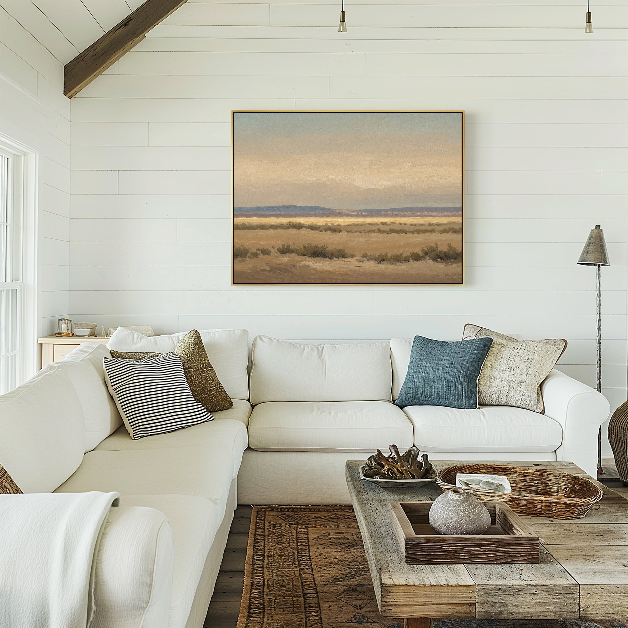 A cozy living room with a white sectional sofa, blue accent pillows, a rustic wooden coffee table, and serene decor featuring the Desert Solitude Canvas Art - Horizontal on the shiplap wall. Natural light streams in from the left.