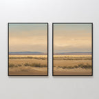 Desert Solitude - Set of 2 features framed southwestern landscape art with sandy plains, low shrubs, distant mountains, and a pale blue sky with soft clouds displayed side by side on a white wall.