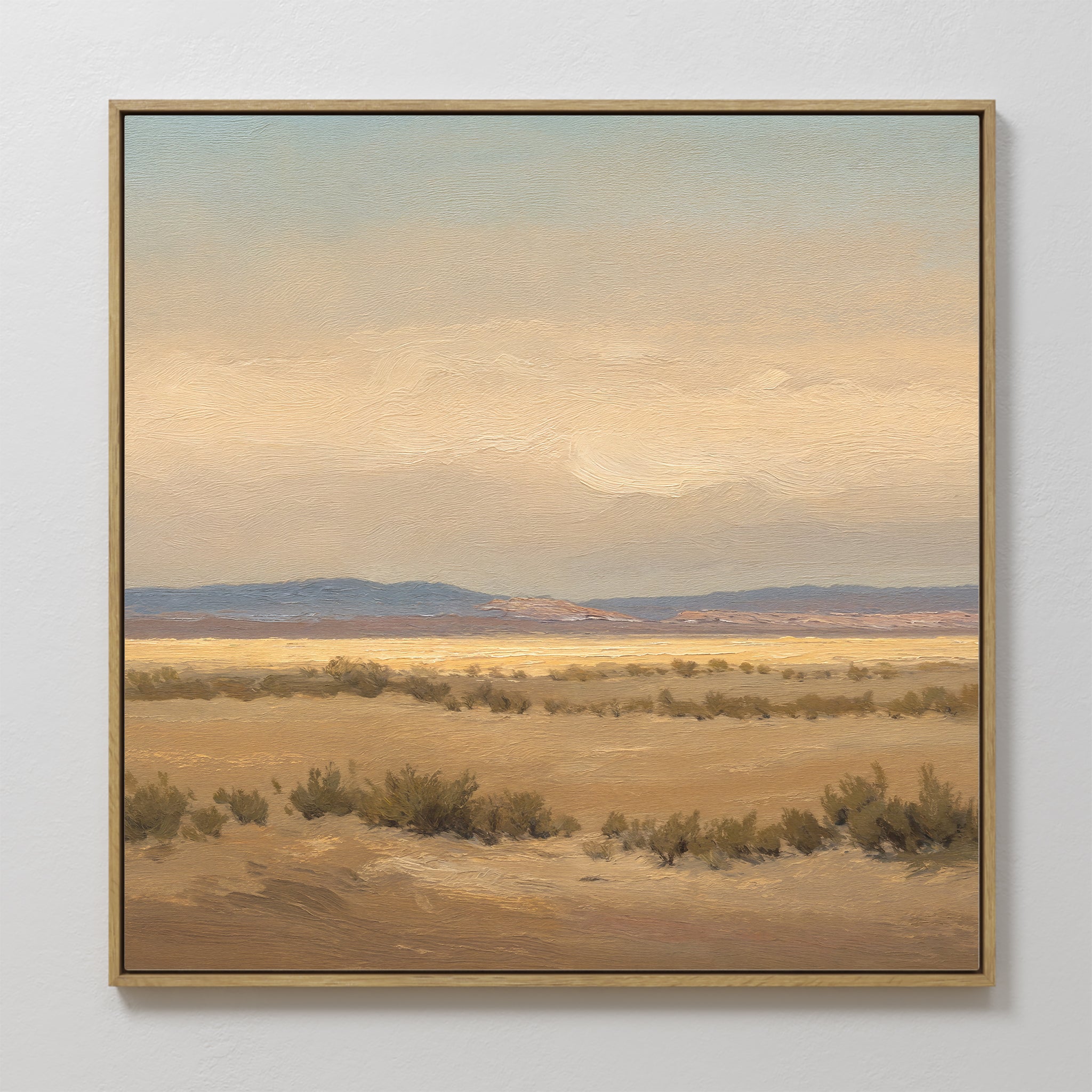 Desert Solitude Canvas Art - Square features a framed canvas print of a calm desert landscape with low bushes, distant mountains, and soft clouds in warm, muted tones—ideal southwestern art for serene wall decor.