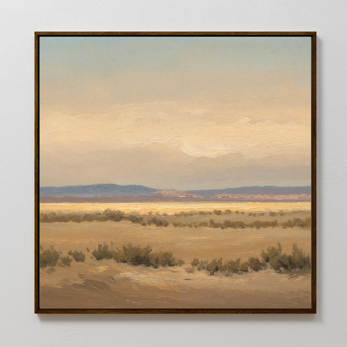 Desert Solitude Canvas Art - Square features a framed print of an open desert with dry bushes, distant hills, and soft clouded skies. Muted earth tones add calm, making it perfect wall decor for fans of southwestern landscape art.