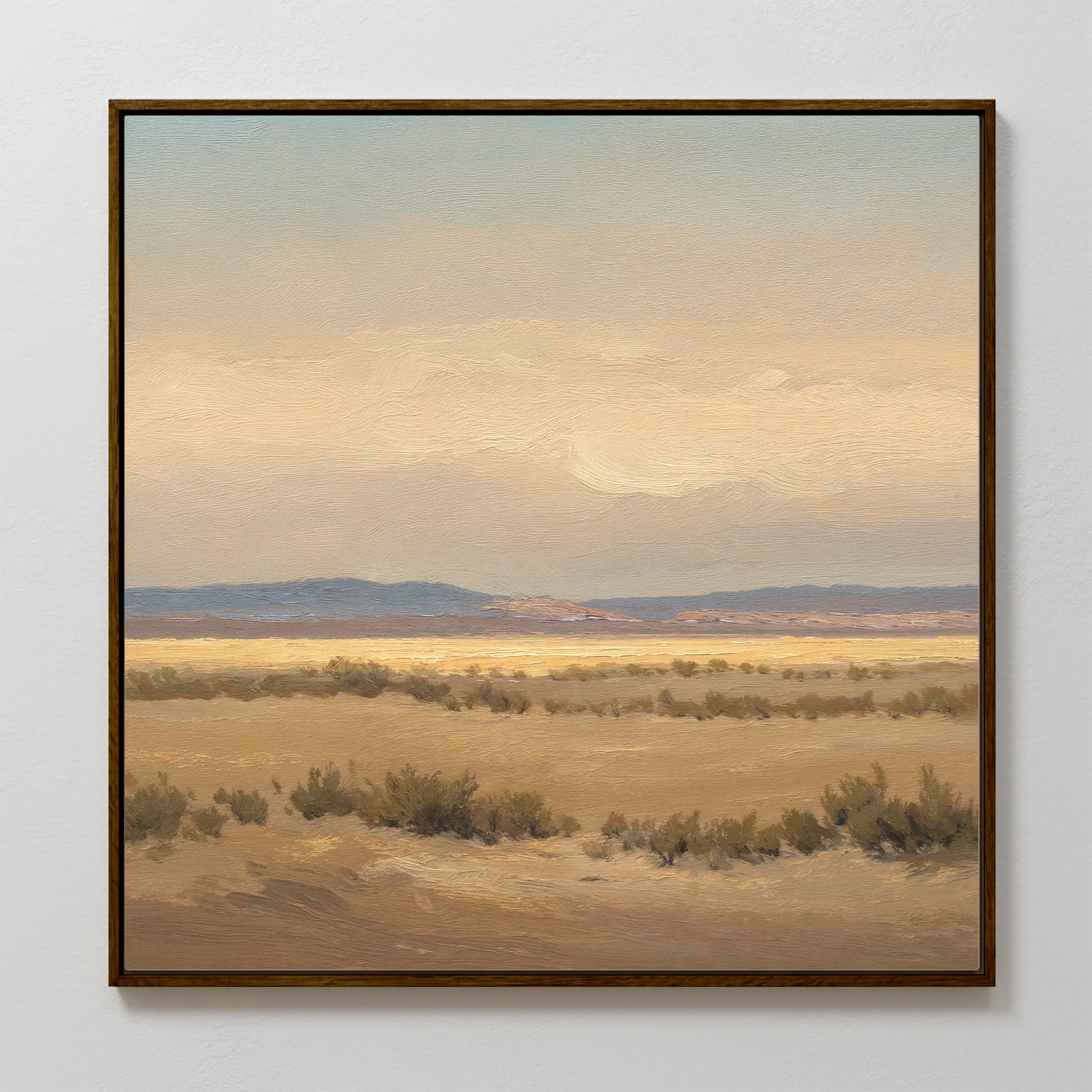Desert Solitude Canvas Art - Square features a framed print of an open desert with dry bushes, distant hills, and soft clouded skies. Muted earth tones add calm, making it perfect wall decor for fans of southwestern landscape art.