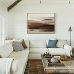 A bright living room with white shiplap walls, a large white sectional, assorted cushions, a rustic wooden coffee table, and the Desert Winds Canvas Art - Horizontal in earthy abstract tones displayed above the sofa.