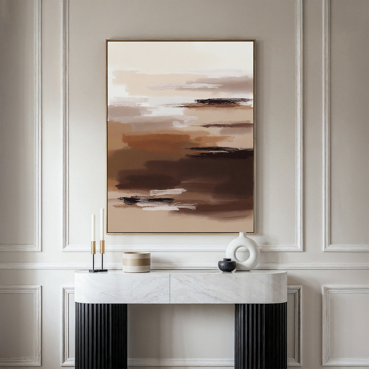 A minimalist console table with decorative objects stands against a wall, topped by the Desert Winds Canvas Art - Vertical, an abstract earth-toned piece. Elegant white panel molding on the wall evokes the serene style of Nordic Park interiors.