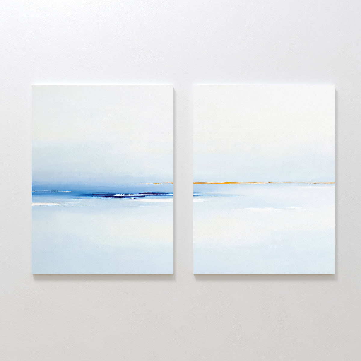 The "Distant Archipelago - Set Of 2" features minimalist prints in soft blue, white, and beige tones that evoke a calm seascape—ideal contemporary wall art for creating a serene atmosphere.