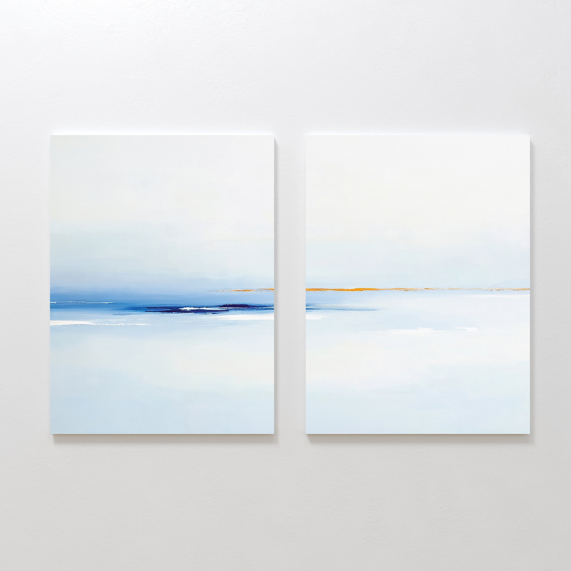 The "Distant Archipelago - Set Of 2" features minimalist prints in soft blue, white, and beige tones that evoke a calm seascape—ideal contemporary wall art for creating a serene atmosphere.