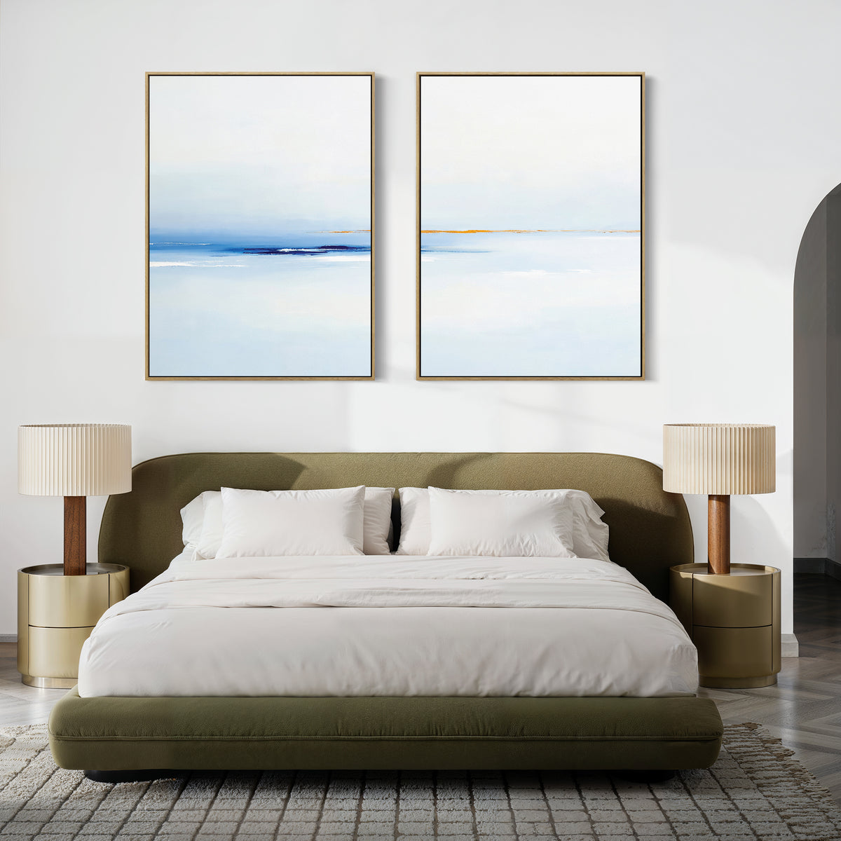 A modern bedroom featuring a green upholstered bed with white bedding, two beige nightstands with matching lamps, and the Distant Archipelago - Set Of 2 blue and white wall art above the bed for a fresh, stylish touch.