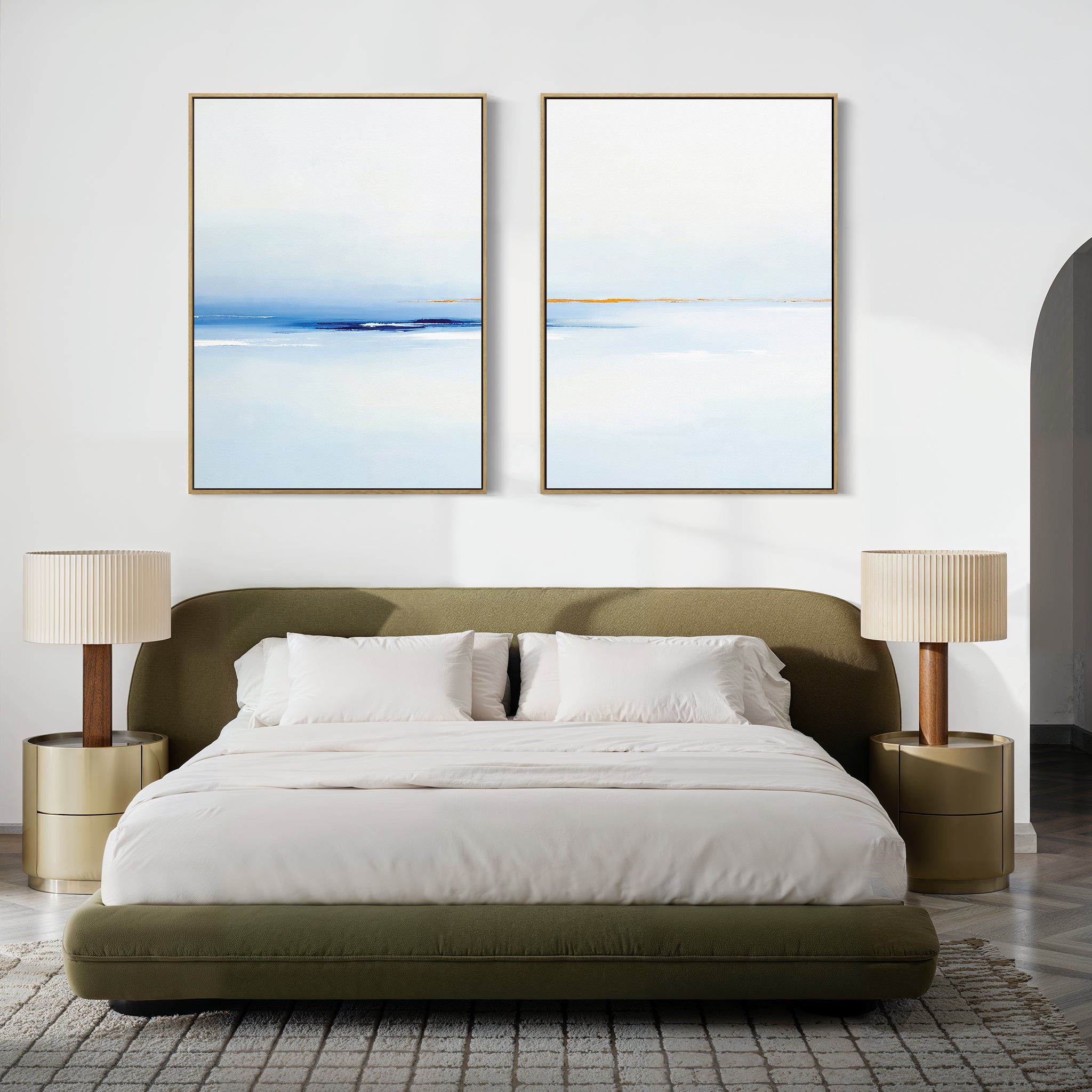 A modern bedroom featuring a green upholstered bed with white bedding, two beige nightstands with matching lamps, and the Distant Archipelago - Set Of 2 blue and white wall art above the bed for a fresh, stylish touch.
