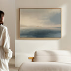A woman gazes thoughtfully at the Distant Isles Canvas Art - Horizontal, adding a touch of tranquil home decor to her space.