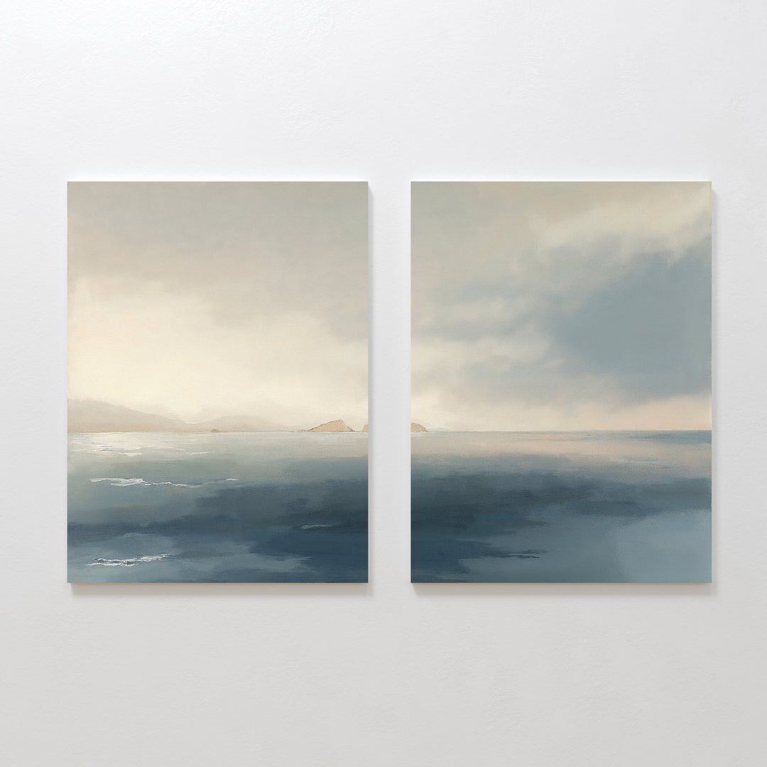 Distant Isles - Set of 2 displays two square canvas prints with calm blue water, distant low hills, and a soft cloudy sky in muted tones—a minimal, serene seascape that brings peaceful style to any space.