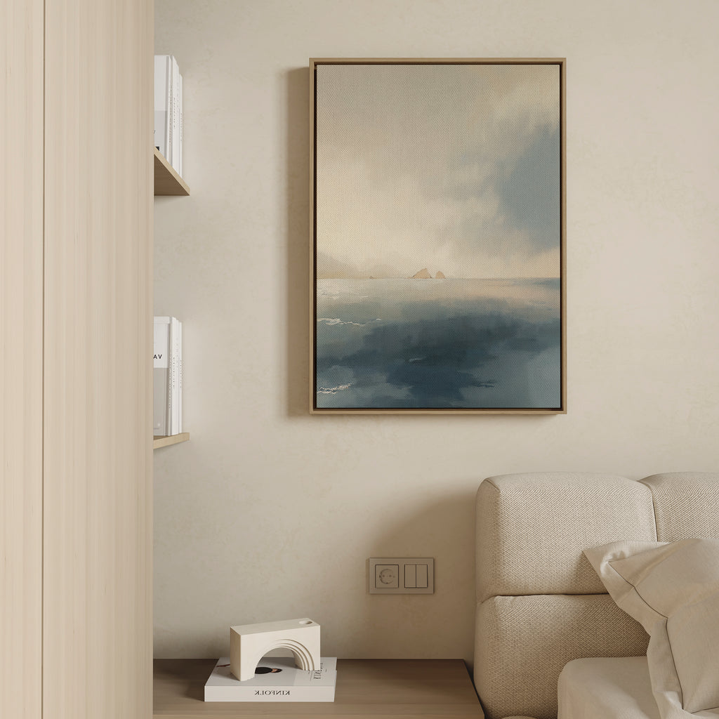 A minimalist living room corner features a beige couch, wooden shelves with white books, and the Distant Isles Canvas Art - Vertical. A small geometric sculpture on a lower shelf adds to the Nordic Park-inspired calm.