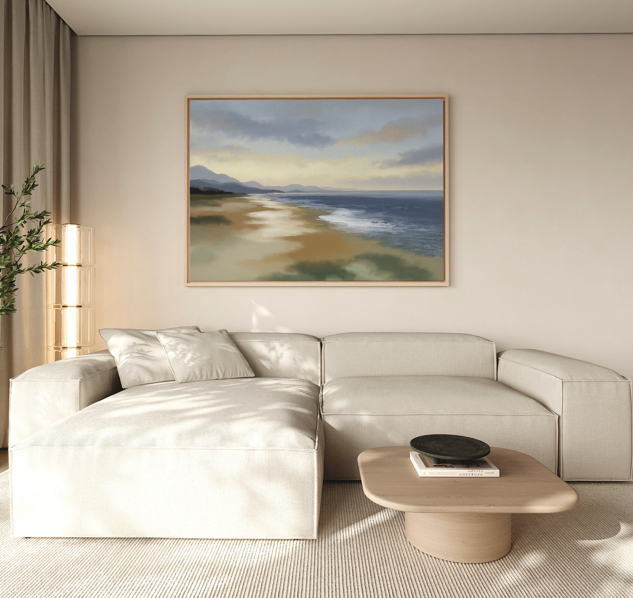A modern living room features a beige sectional sofa, light wood coffee table, and the Distant Shores Canvas Art - Horizontal above the sofa. Soft natural light and a corner plant further enhance the tranquil coastal ambiance.