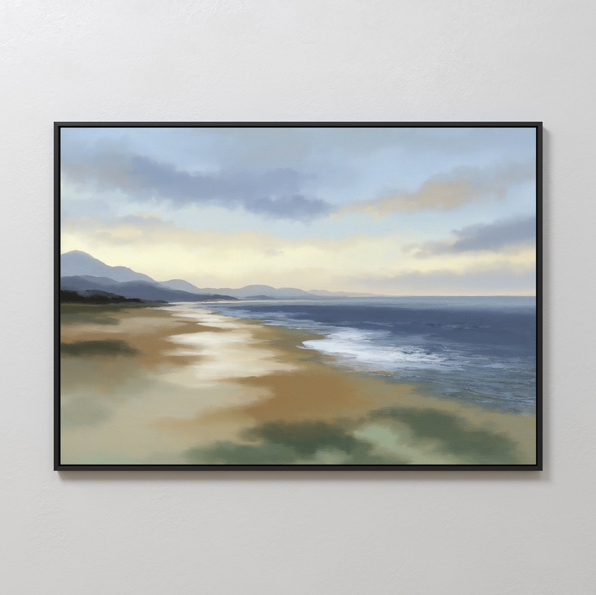 The Distant Shores Canvas Art - Horizontal features a tranquil beach with gentle waves, sandy shore, distant mountains, and a softly lit cloudy sky, beautifully framed and displayed on a plain white wall.