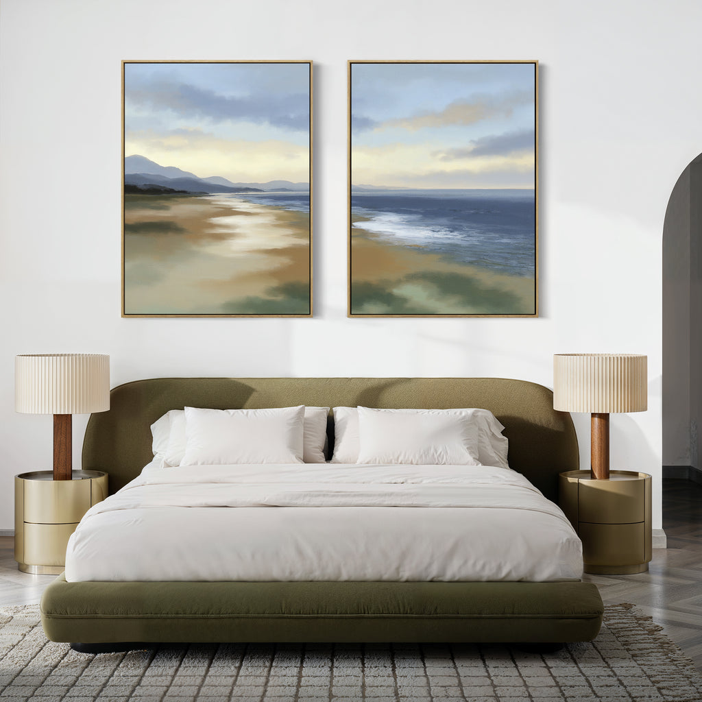 Modern bedroom with an olive green bed, neutral bedding, two round side tables with lamps, textured rug, and the "Distant Shores - Set of 2" coastal panorama canvas prints featuring a serene beach and ocean above the bed.