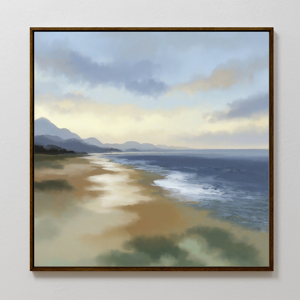 The Distant Shores Canvas Art - Square features a framed coastal panorama with a sandy beach, gentle waves, distant mountains, and a cloudy sky illuminated by soft sunlight reflected on the water and shore.