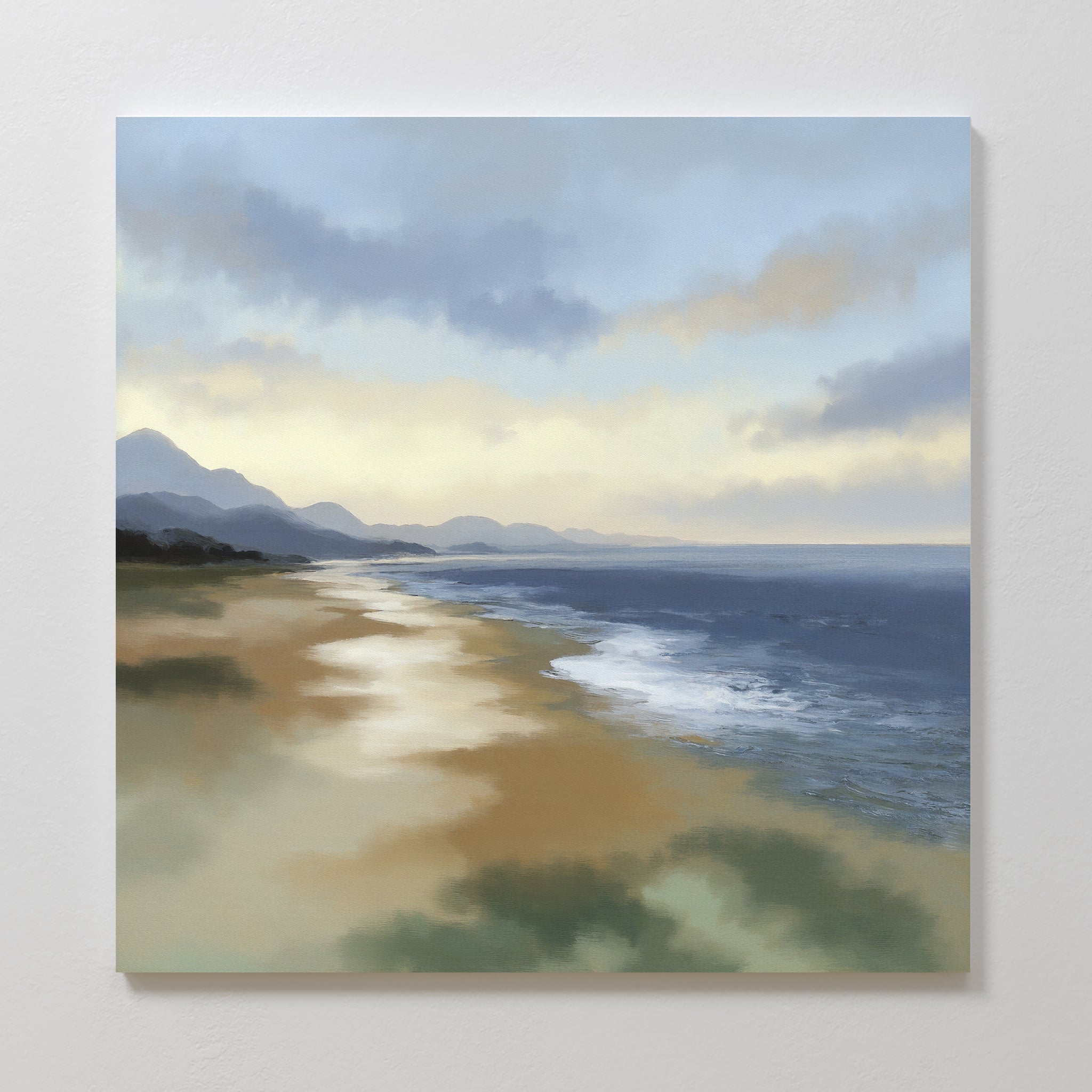 The Distant Shores Canvas Art - Square depicts a serene beach at sunset with gentle waves on the shore, distant mountains, and a cloudy sky reflecting warm, soft light.