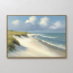 The Dune Whispers Canvas Art - Horizontal, featuring a sandy beach with grassy dunes, gentle waves, and a partly cloudy sky, is displayed against a plain white wall.
